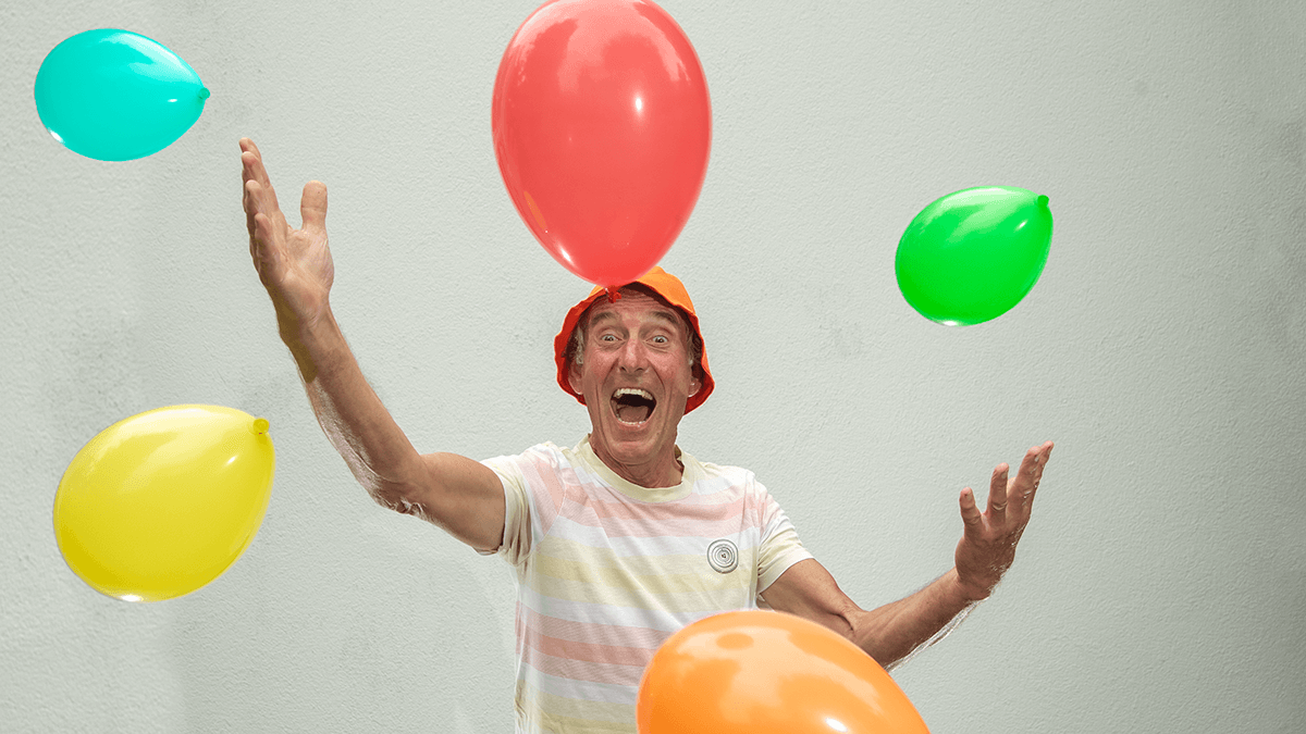 Foto van Cor van Ruijven van CvR VISIE die blij ballonnen voor zich uitgooit.